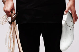 Artisan shoe brands represented by a craftsman holding shoemaking tools and a wooden shoe last.