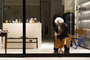 Bespoke shoes displayed in a minimalist workshop with a shoemaker working under warm lighting