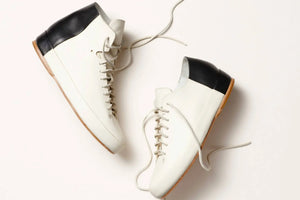 Handmade shoes in a white and black high-top design, showcasing fine leather details and quality construction