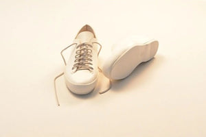 Shoe welting process shown with white leather sneakers cut open to reveal construction layers.