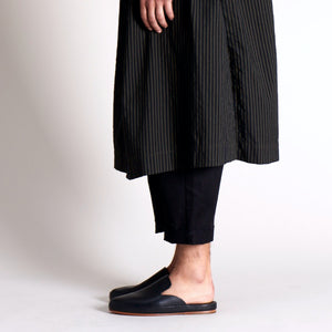Black handmade mules styled with cropped black pants and a pinstriped long coat.