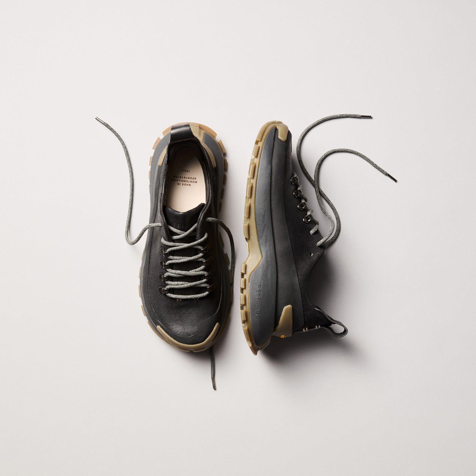 FEIT black trail shoe shown from above and side, highlighting the Montebelluna-made leather upper and Vibram sole profile.